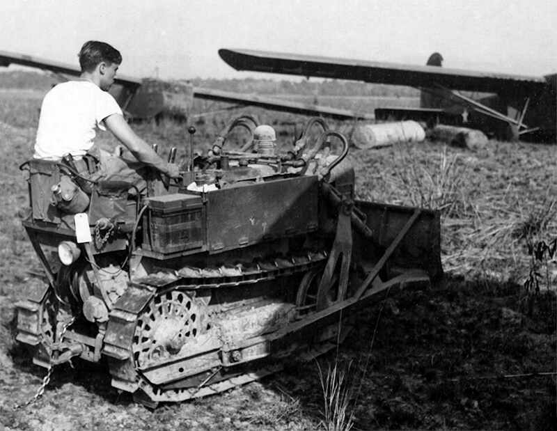 Engineers of the 900th Airborne Engineer Aviation Company using a Jeep to remove stumps from Broadway, note the airborne engineer insignia on the windscreen.