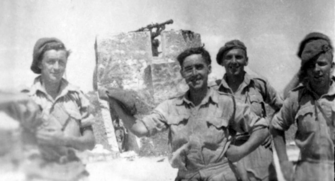 The men of the Special Raiding Squadron celebrate after successfully capturing Battery AS 493, with the rangefinder tower of the battery visible in the background.