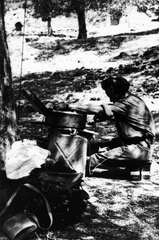 SERVICE OF MAJOR DAVID SMILEY WITH SPECIAL OPERATIONS EXECUTIVE (SOE) IN ALBANIA, 1943 -    1944. (HU 64784) Second mission: Radio operator Corporal Davis with B2 suitcase wireless set (resting on gerry cans) at Mukaj, August 1944. Copyright: ý IWM. Original Source: http://www.iwm.org.uk/collections/item/object/205060987