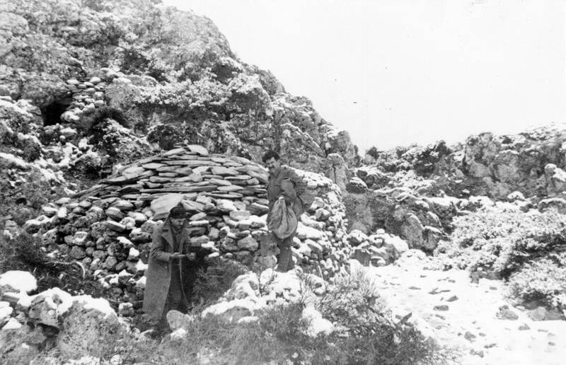 SOE (SPECIAL OPERATIONS EXECUTIVE) AND CRETAN PARTISANS ON CRETE, 1 JUNE 1944 - 28    FEBRUARY 1945. (HU 66089) Two partisans stand in front of their stone built hut in the snow covered Cretan hills. Copyright: ý IWM. Original Source: http://www.iwm.org.uk/collections/item/object/205045479