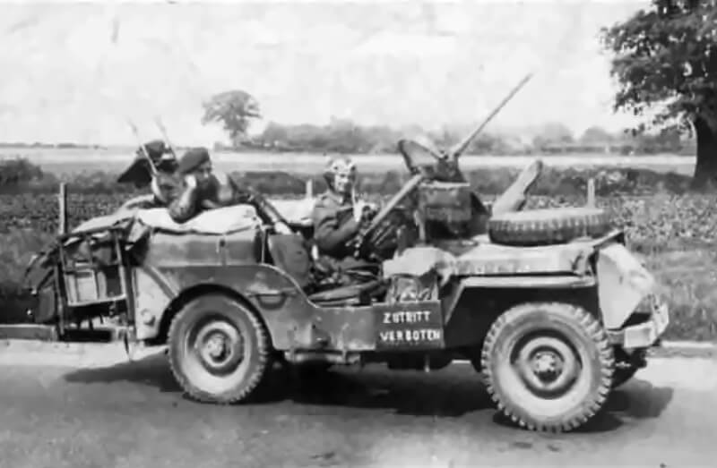 A SAS jeep rumbles through occupied territory with a stolen sign fixed to its front, "Zutritt Verboten", the stark German for "No Trespassing".