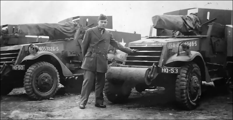 Second Lieutenant Frank Kennard standing beside his two 75-millimetre cannon half-tracks in Bude, Cornwall.