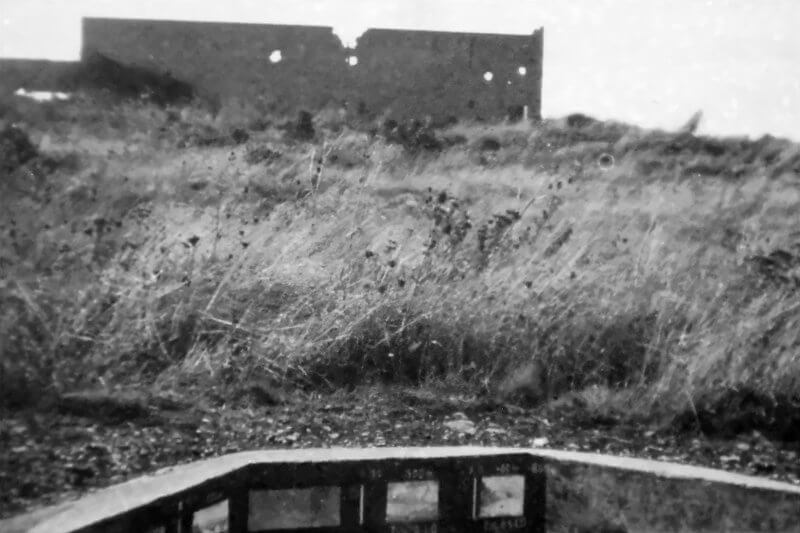 Photo from Tobruk mortar opening, looking west, with the ruins of Maison Gambier visible in the background.