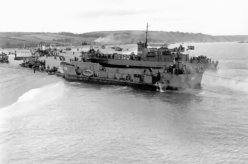 Centre of the beach during an exercise, with the smoking remains of the Royal Sands Hotel visible in the background.