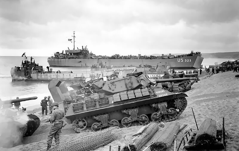 US M10 tank destroyers coming ashore at Slapton Sands, with LST 325 visible in the background.