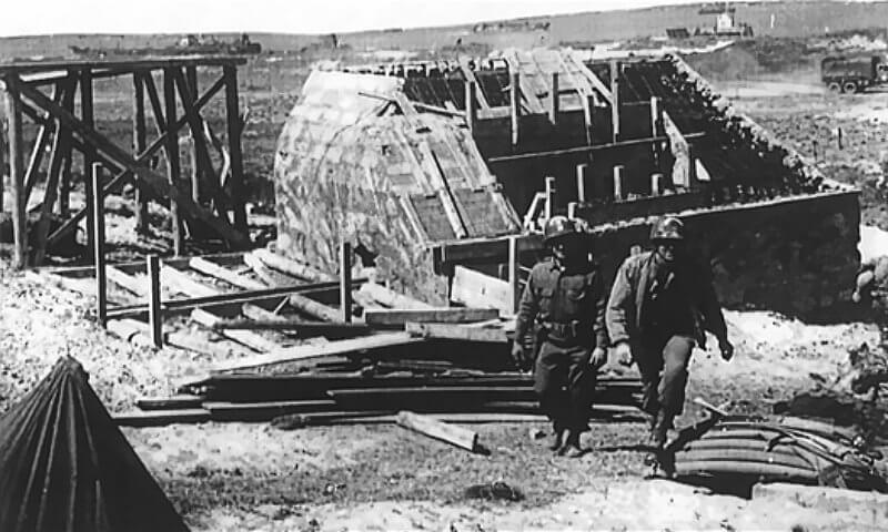 Unfinished H667 casemate at WN65, with two 5th Engineer Special Brigade soldiers identified by white semi-circular helmet markings.