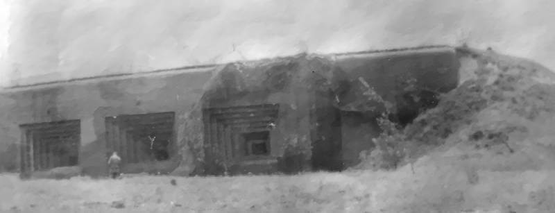 A German soldier stands in front of one of Fort Eben-Emael’s massive artillery fortifications, illustrating the scale and strength of the fortress’ concrete defences.