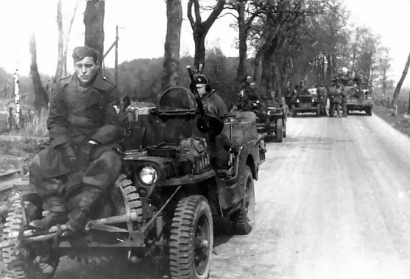 April 1945, Oosterhesselen. A Belgian SAS jeep carries a prisoner of war on the hood.