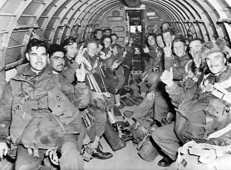 September 17th, 1944. No. 5 Platoon, S Company, 1st Battalion, before takeoff for the Netherlands. From left: Sergeant Kelly, Hellier, Corporal Court, Fairweather, Lance-Corporal Brown, unknown, Cortman, Tidbal, five unknown, Sergeant Reynolds, McAnelly, Corporal Mount, Gibbons.